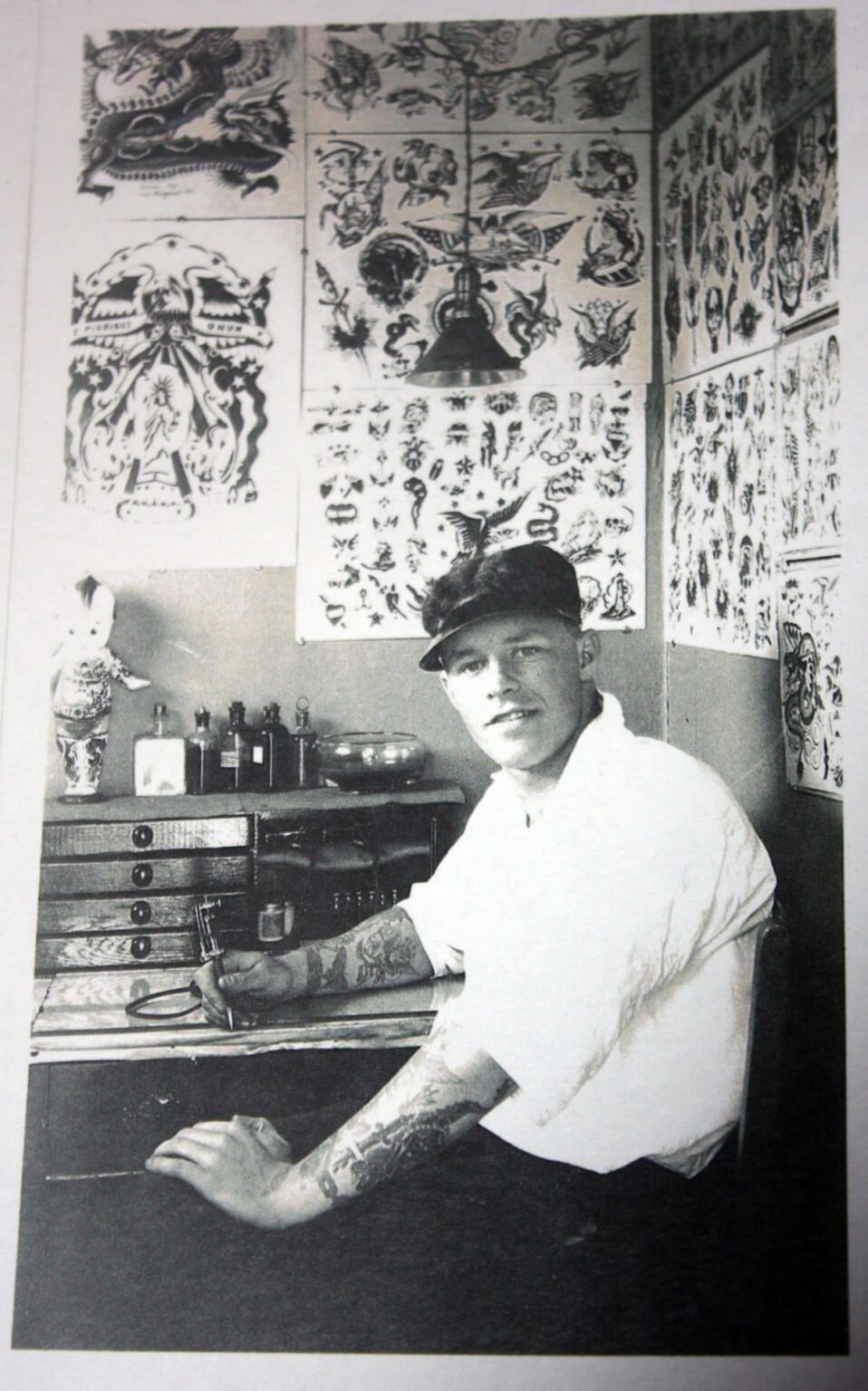 Tatoueur travaillant dans un atelier ancien entouré de flashs old school