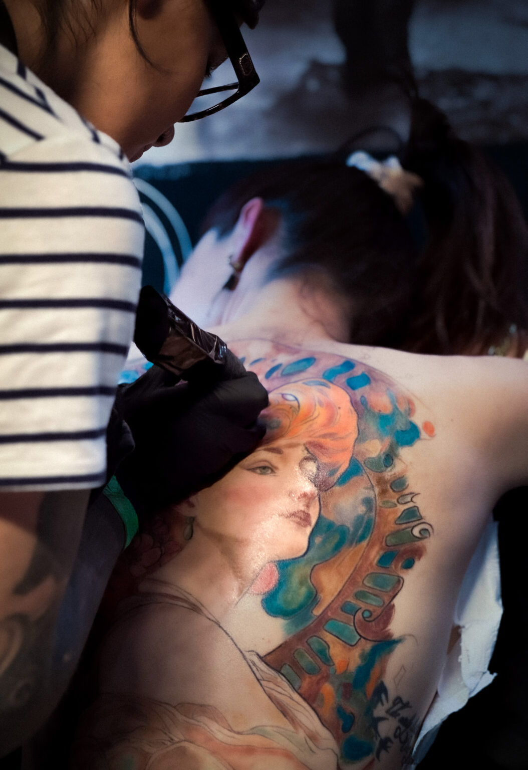 Tatouage féminin art nouveau en couleur dans le dos, inspiration Alphonse Mucha, réalisé par Tamara Chaudesaigues.