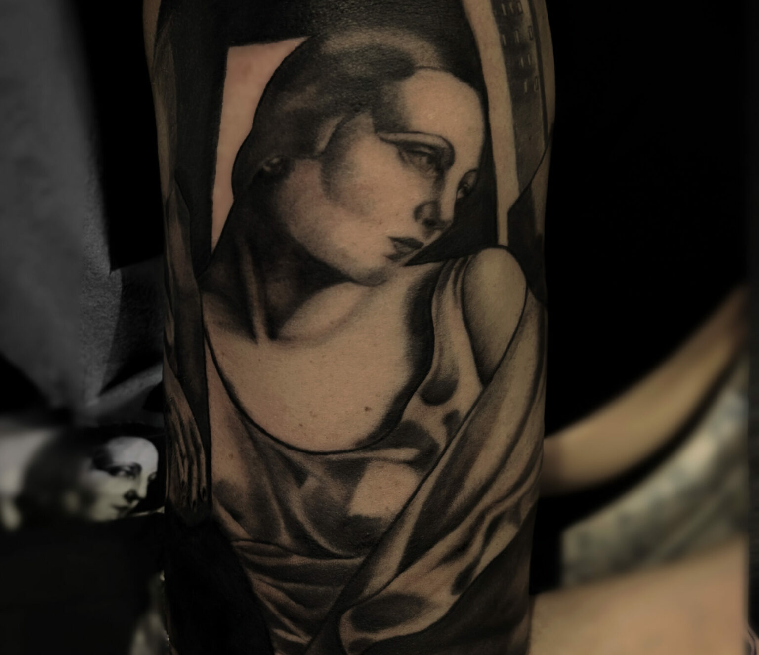 Tatouage noir et gris inspiré de Tamara de Lempicka, portrait féminin art déco aux volumes sculpturaux, réalisé par Tamara Chaudesaigues, tatoueuse, entre héritage artistique et esthétique urbaine contemporaine.