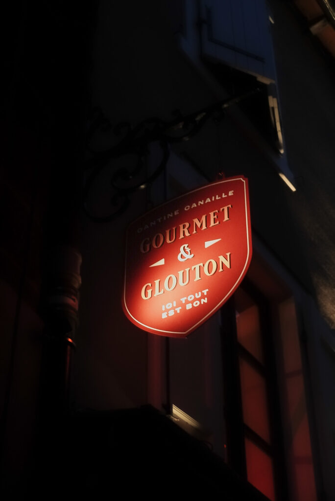 Illuminated Gourmet & Glouton sign at night in Chaudes-Aigues
