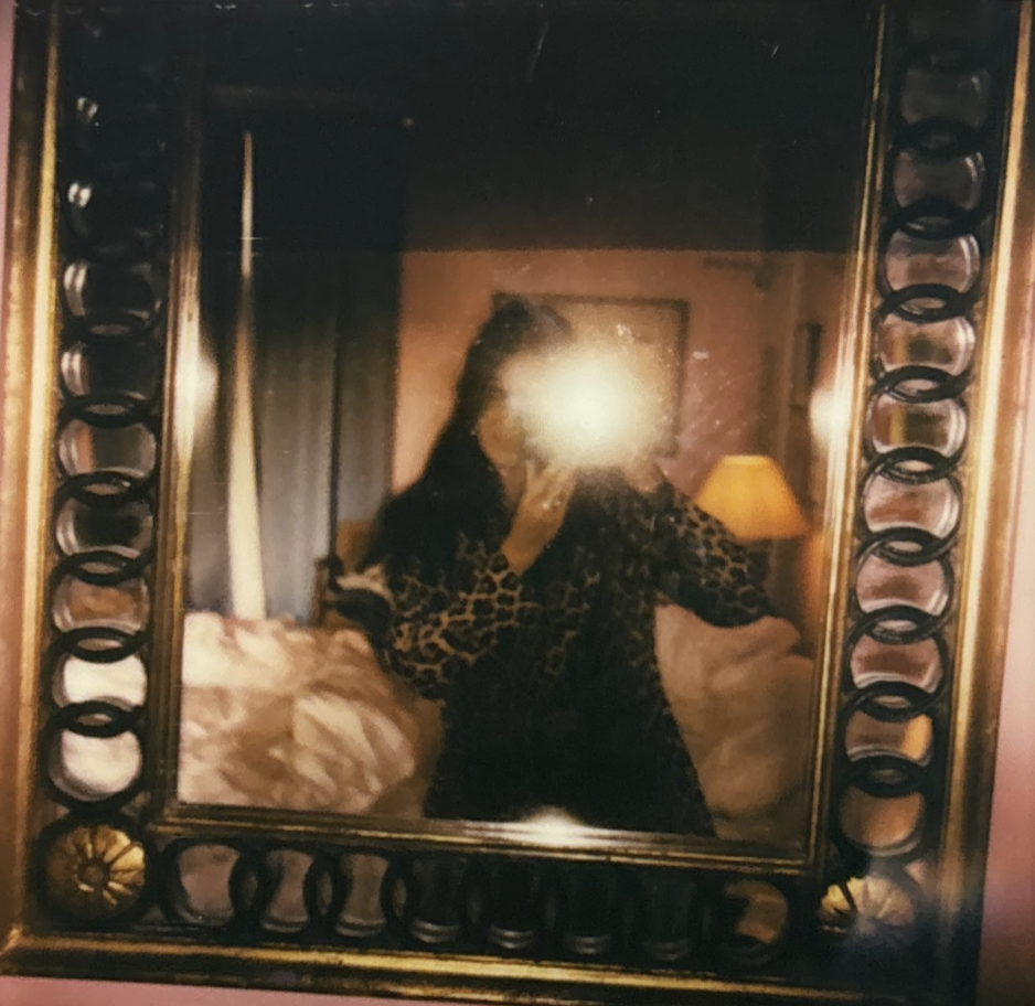 Selfie dans le miroir doré de la chambre rose de l'Hôtel Amour Nice, lumière de chevet chaude