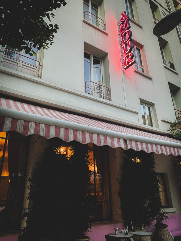 Façade de l’Hôtel Amour à Nice avec auvent rayé rose et enseigne néon