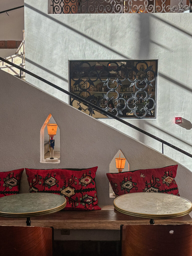 Espace intérieur avec tables rondes et coussins rouges à l’Hôtel Amour Nice