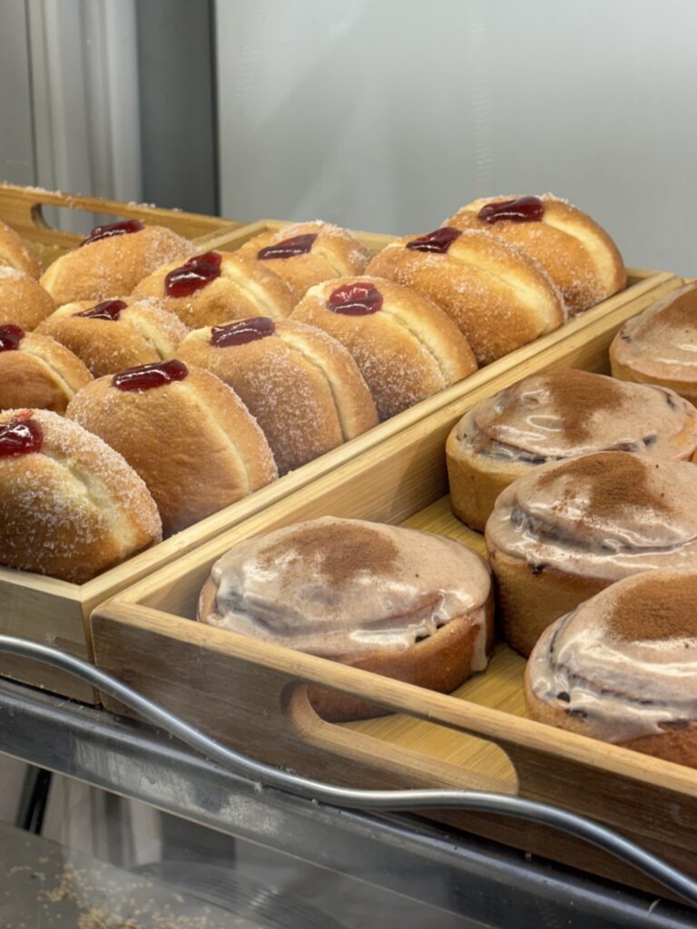 Doughnuts and cinnamon rolls on a tray at Beigel Bake, Brick Lane London
