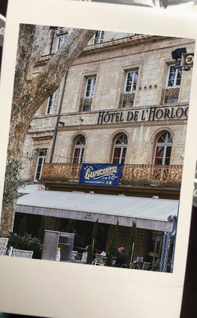 Photo Instax de la bannière Graphicaderme sur la façade de Casa Bronzini place de l'Horloge Avignon