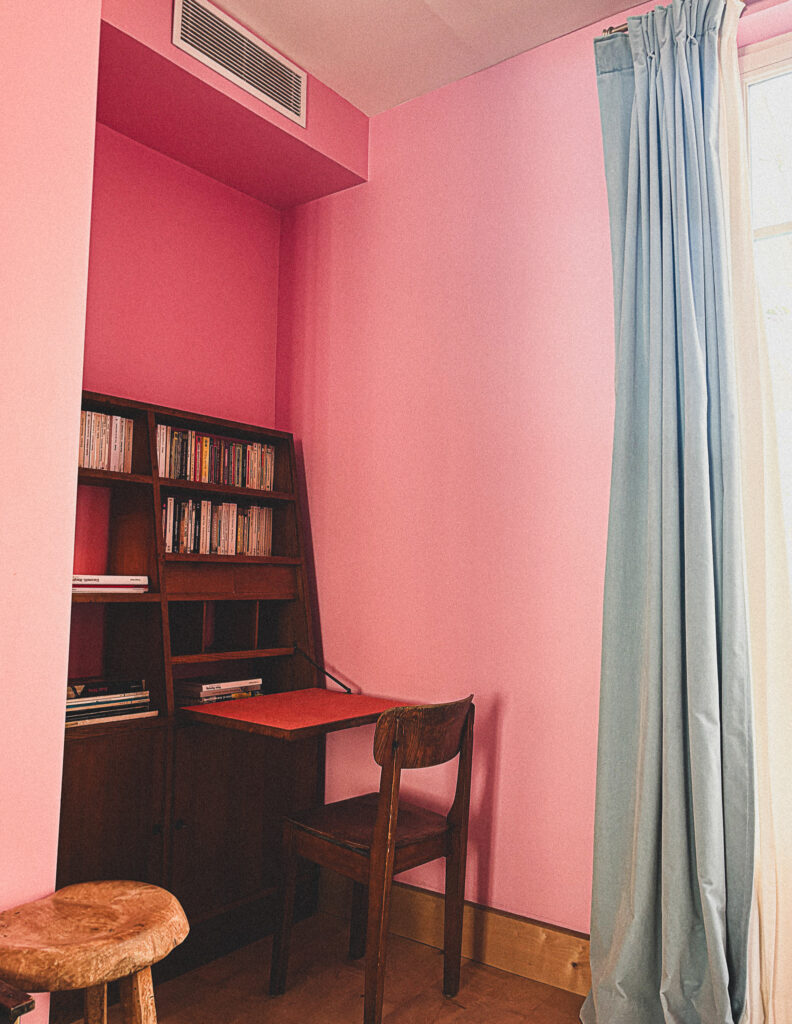 Wooden desk and bookshelves in a pink room at Hôtel Amour Nice