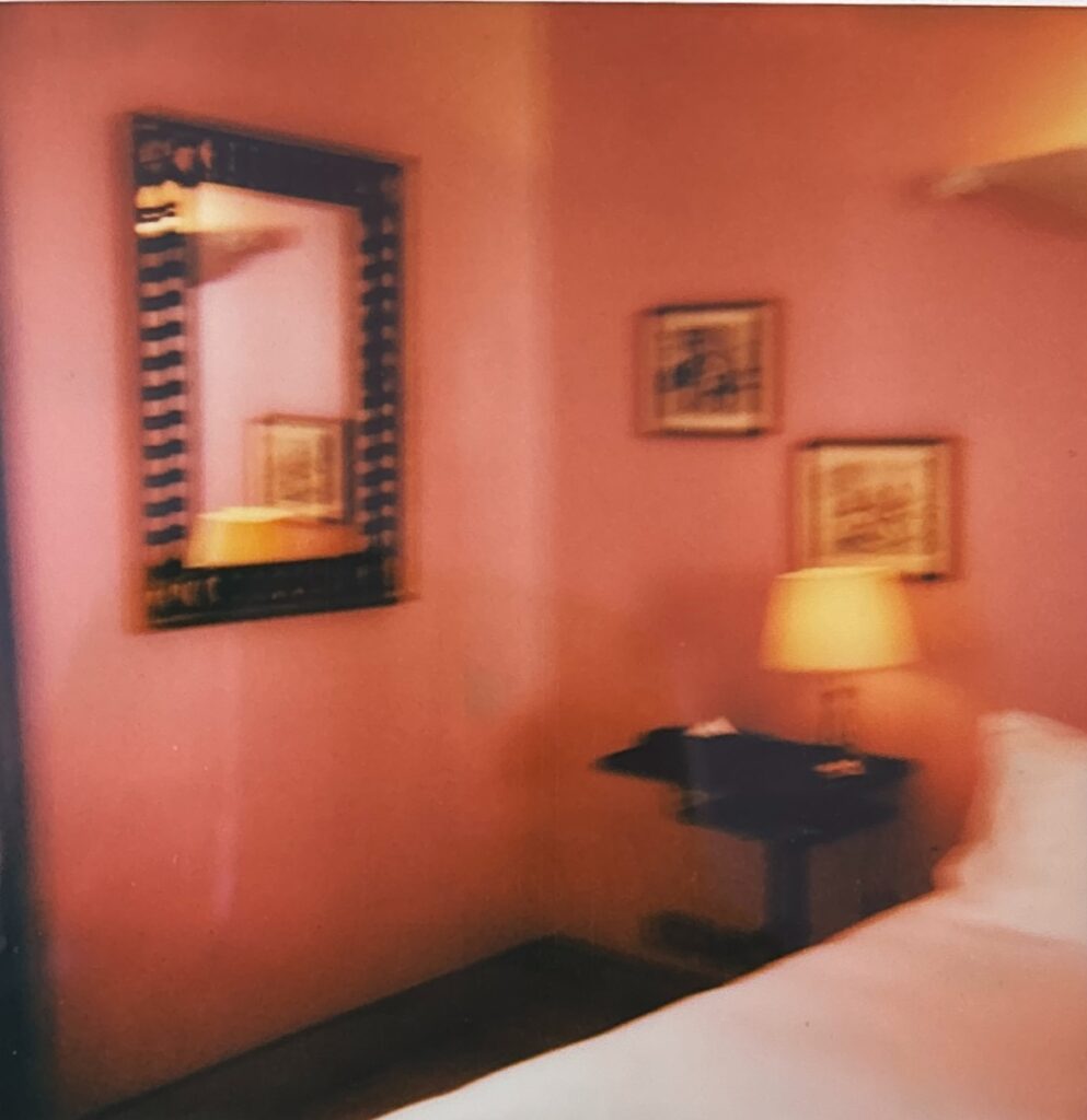 Pink room at Hôtel Amour Nice, wooden mirror, golden bedside lamp and paintings on the wall