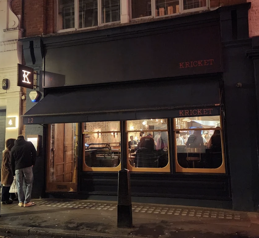 Kricket restaurant facade at night in Soho London, queue outside