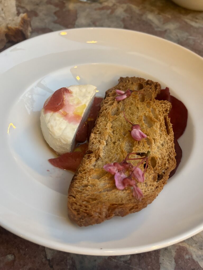 Gros plan chèvre frais pain grillé betterave et fleurs comestibles au restaurant Le Bèou Avignon