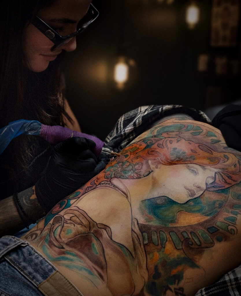 Tamara Chaudesaigues tattooing Art Nouveau colour back tattoo in progress, Graphicaderme Avignon, tattoo artist London
