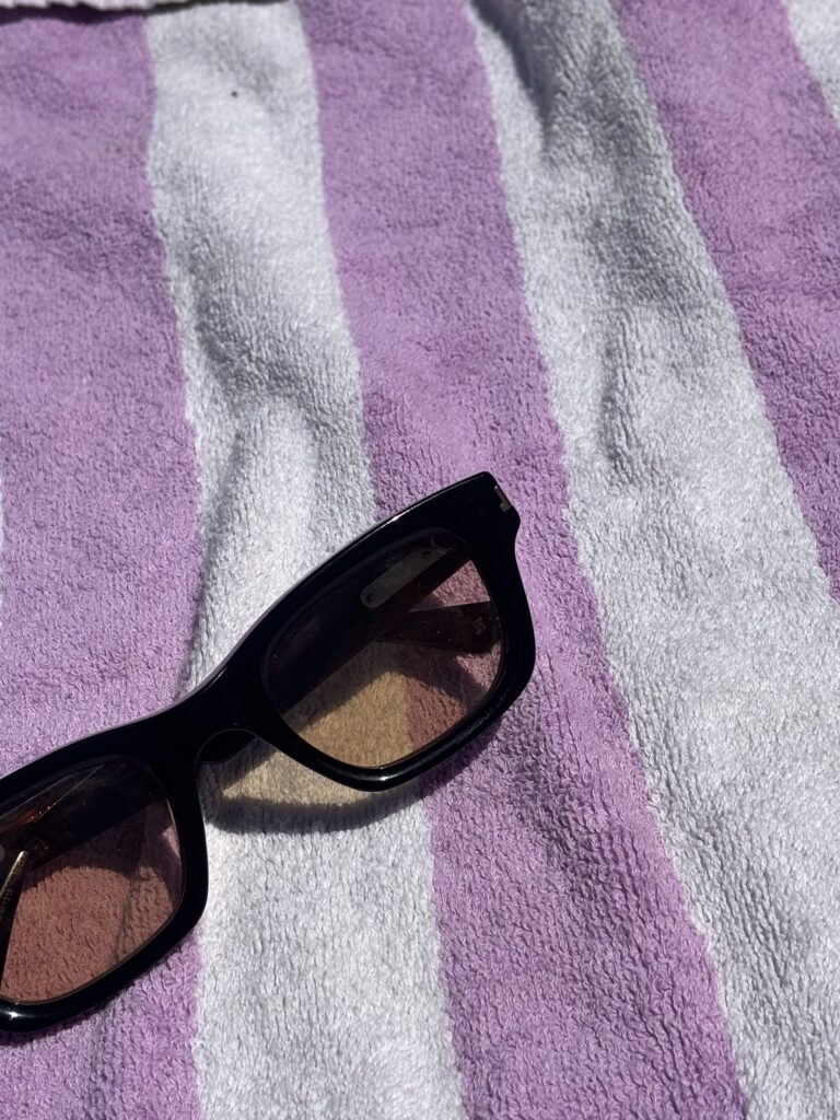 Lunettes de soleil Jimmy Fairly posées sur une serviette de plage