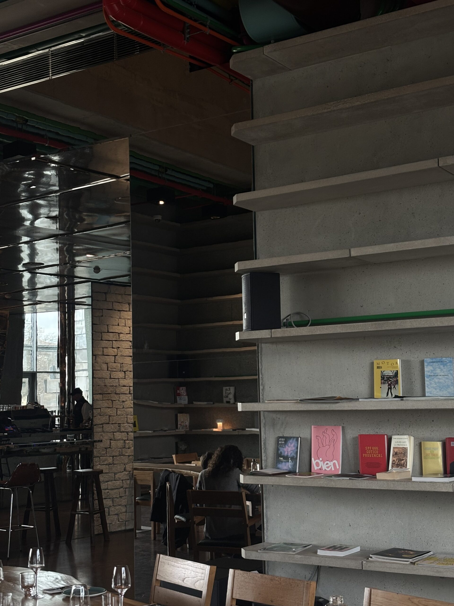 Concrete bookshelves and wooden tables in the Drum Café room at LUMA Arles