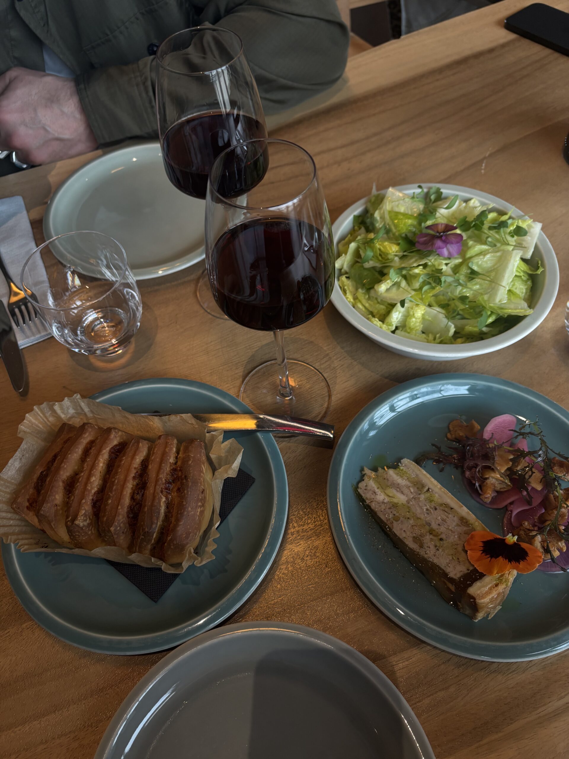 Déjeuner au Drum Café avec pâté en croûte, salade, assiette fleurie et verres de vin rouge
