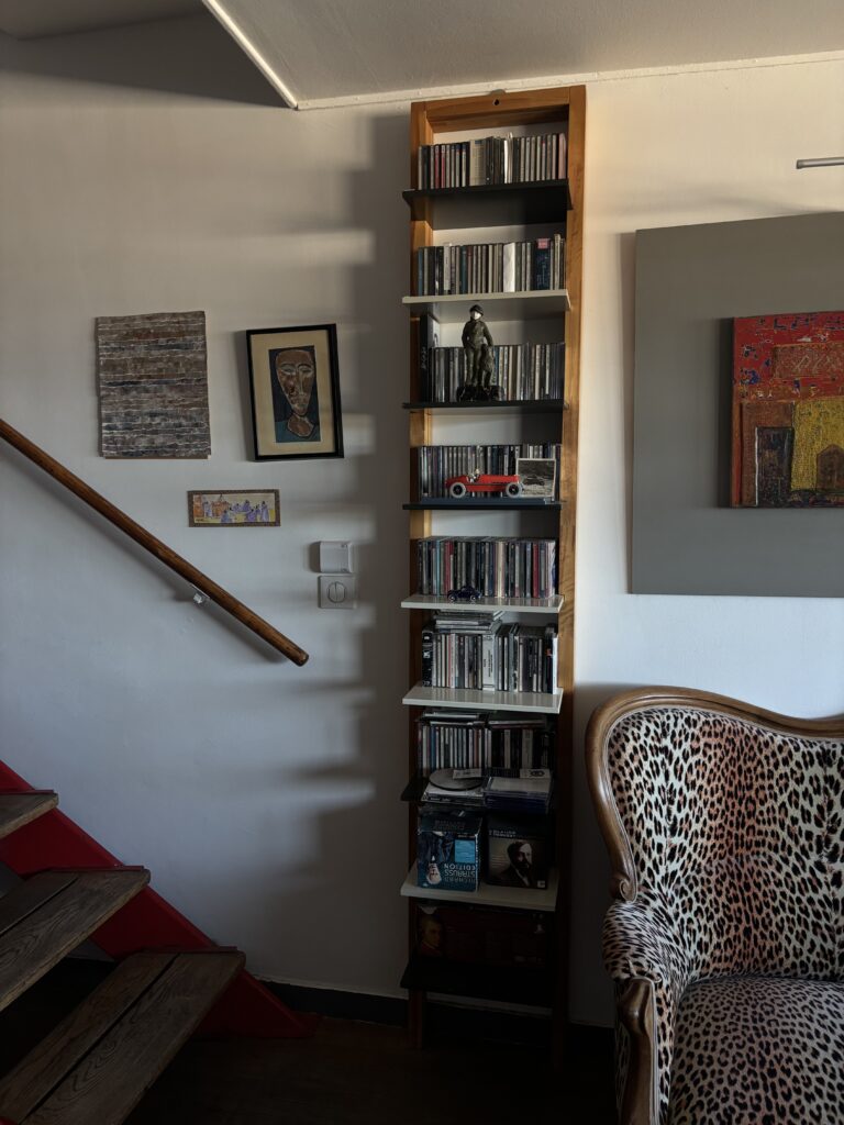 Escalier rouge, bibliothèque, œuvres d’art et fauteuil léopard dans un duplex habité de la Cité Radieuse