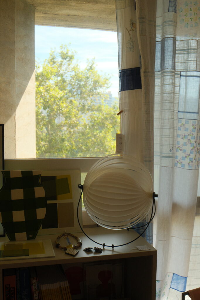 Lampe blanche, bijoux et textiles colorés près de la fenêtre de Maison Mirbel