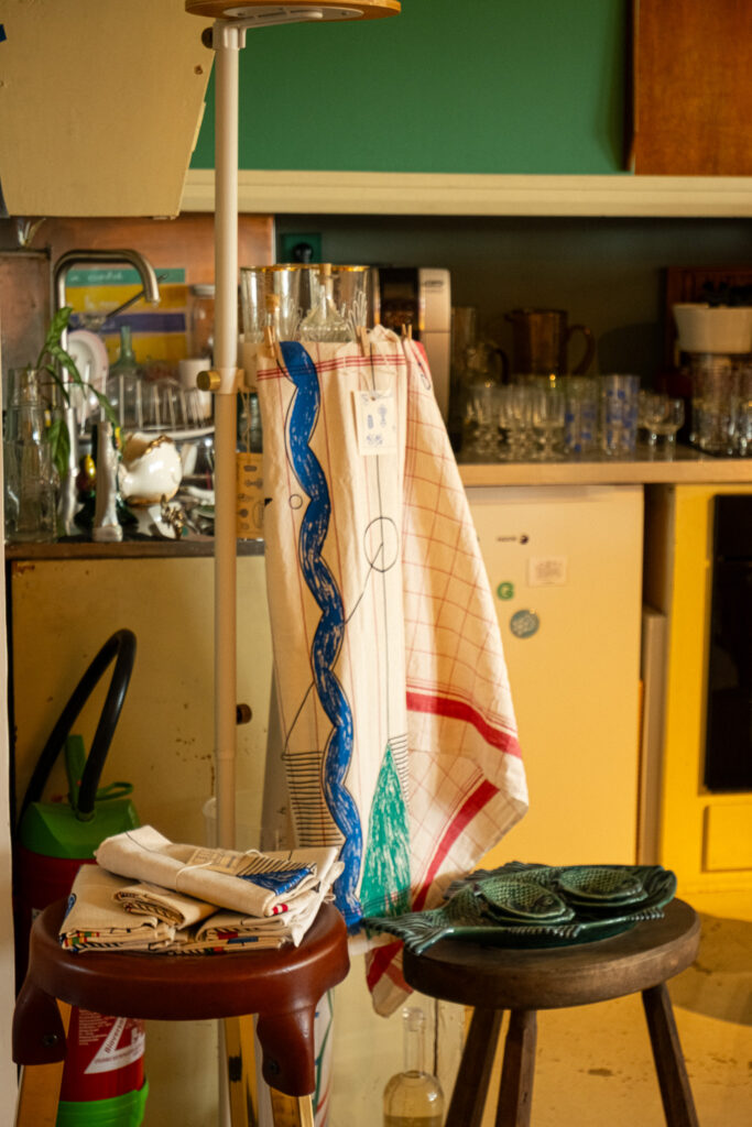 Torchons illustrés et plats en céramique présentés dans la boutique Maison Mirbel