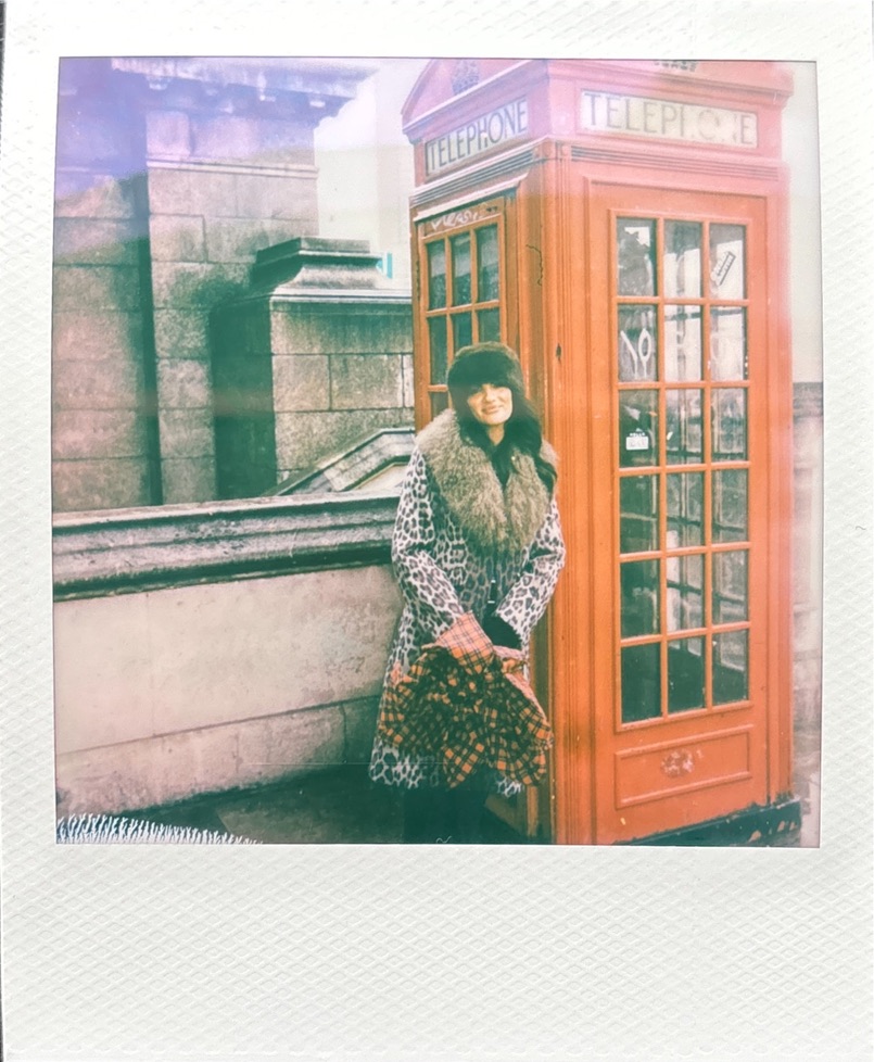 Tamara posant devant une cabine téléphonique rouge à Londres sur une photo Polaroid