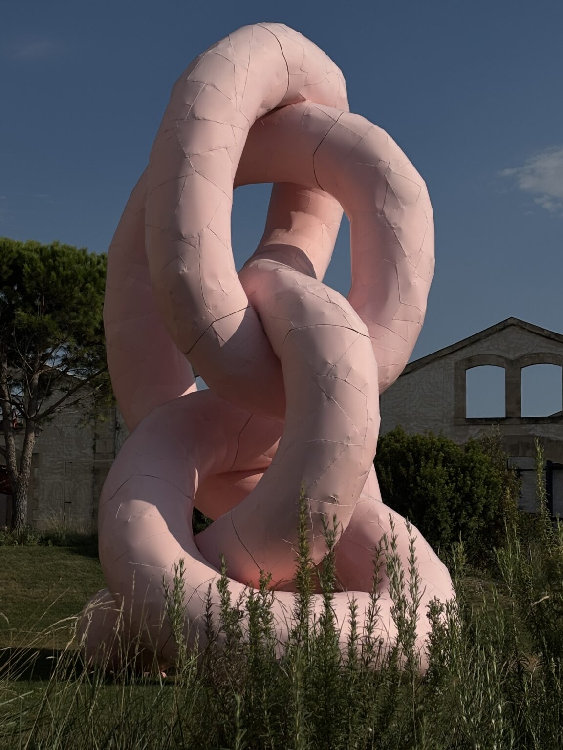 Monumental pink artwork among the greenery at LUMA Arles