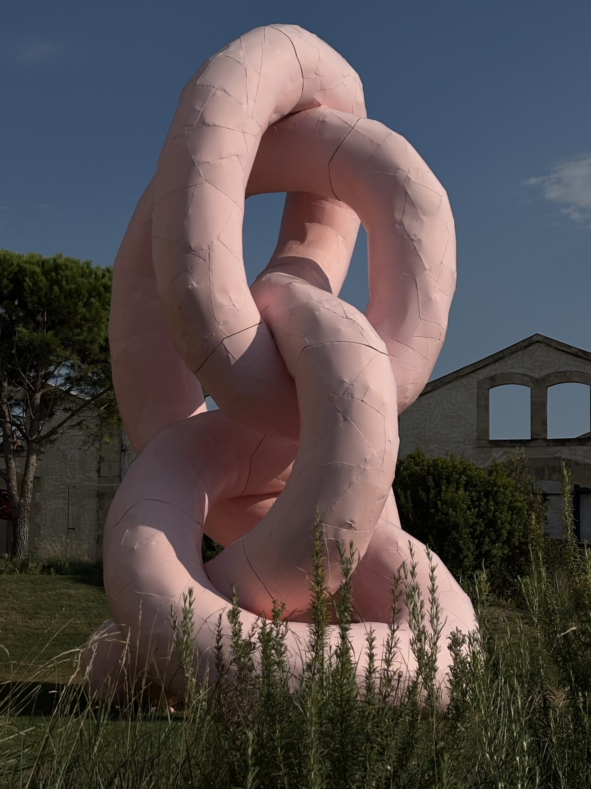 Œuvre rose monumentale entourée de végétation dans le parc de LUMA Arles