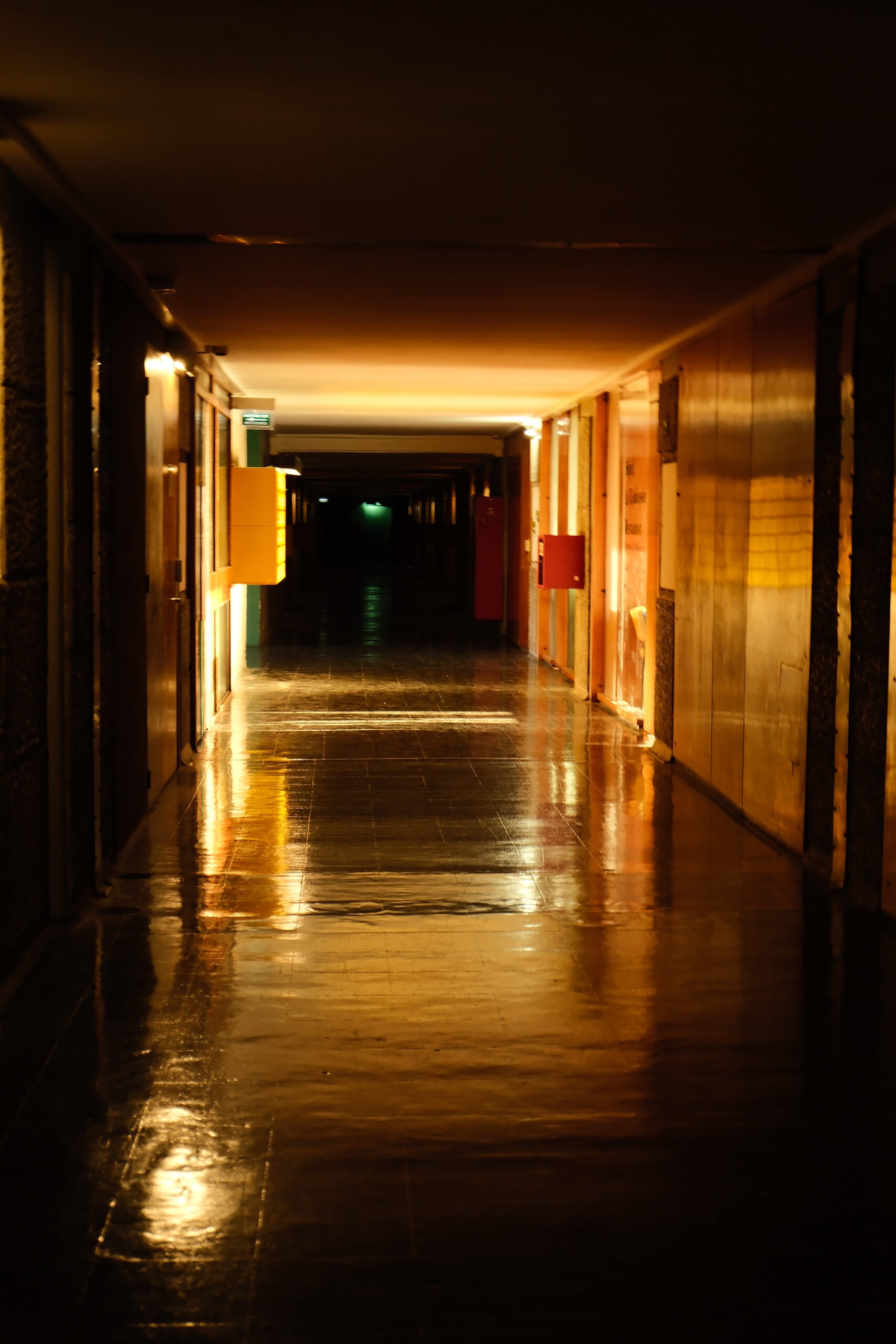 Long couloir sombre de la Cité Radieuse éclairé par des lumières orange et vertes