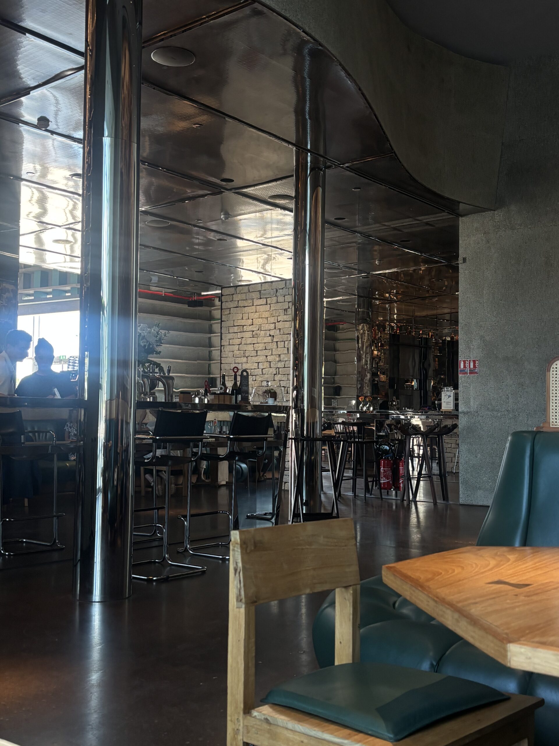 Tables en bois, banquette verte et comptoir du Drum Café à LUMA Arles