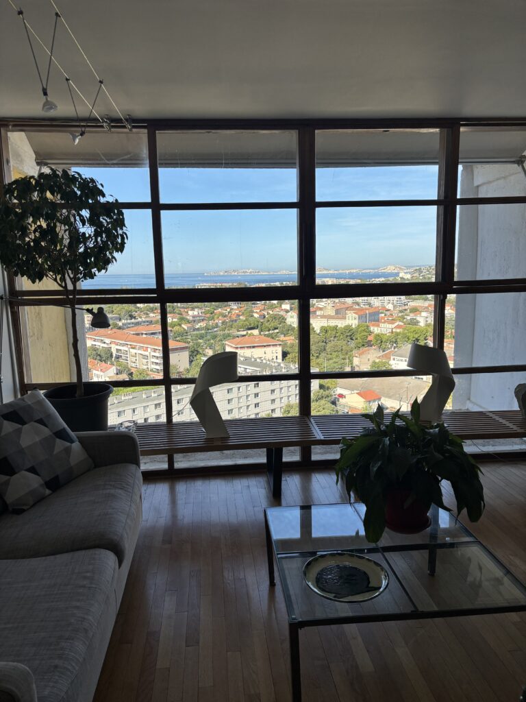 Séjour lumineux d’un duplex de la Cité Radieuse avec grande baie vitrée donnant sur Marseille et la mer