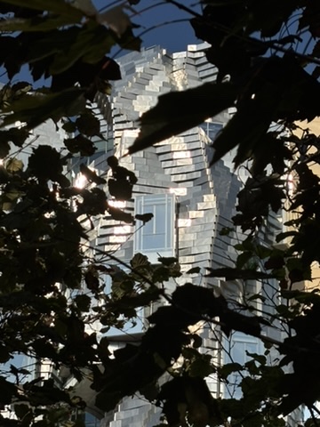 La façade métallique de la tour LUMA aperçue à travers les arbres du parc
