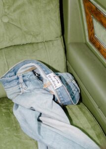 Light blue Acne Studios jeans laid on a green armchair