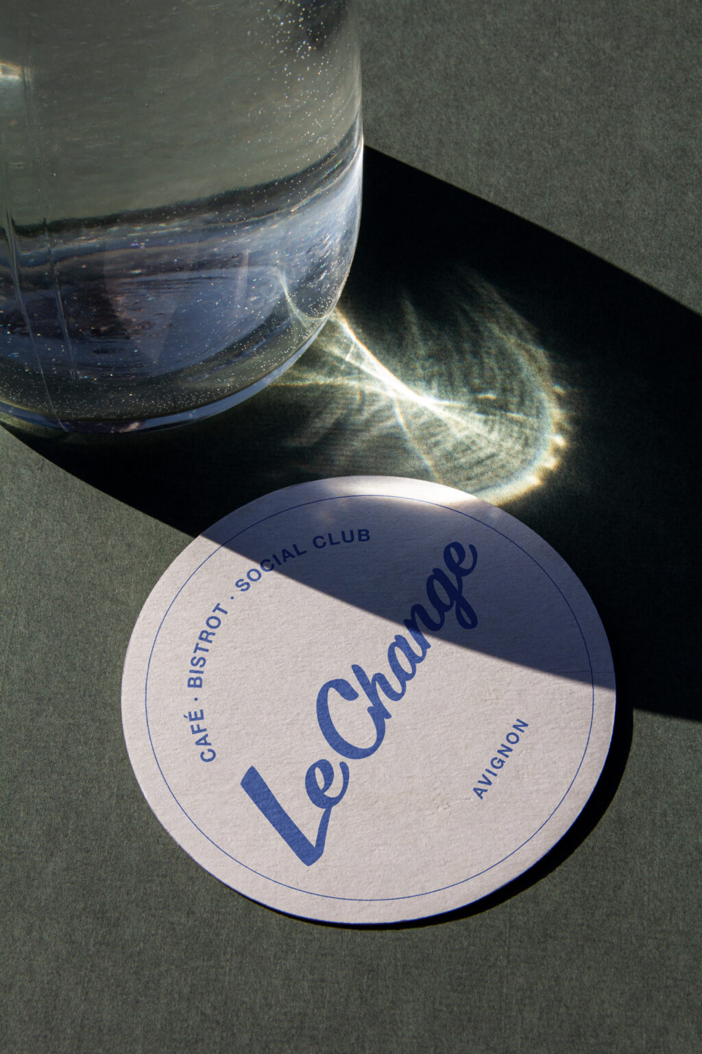 White glass coaster with the blue logo of the restaurant Le Change